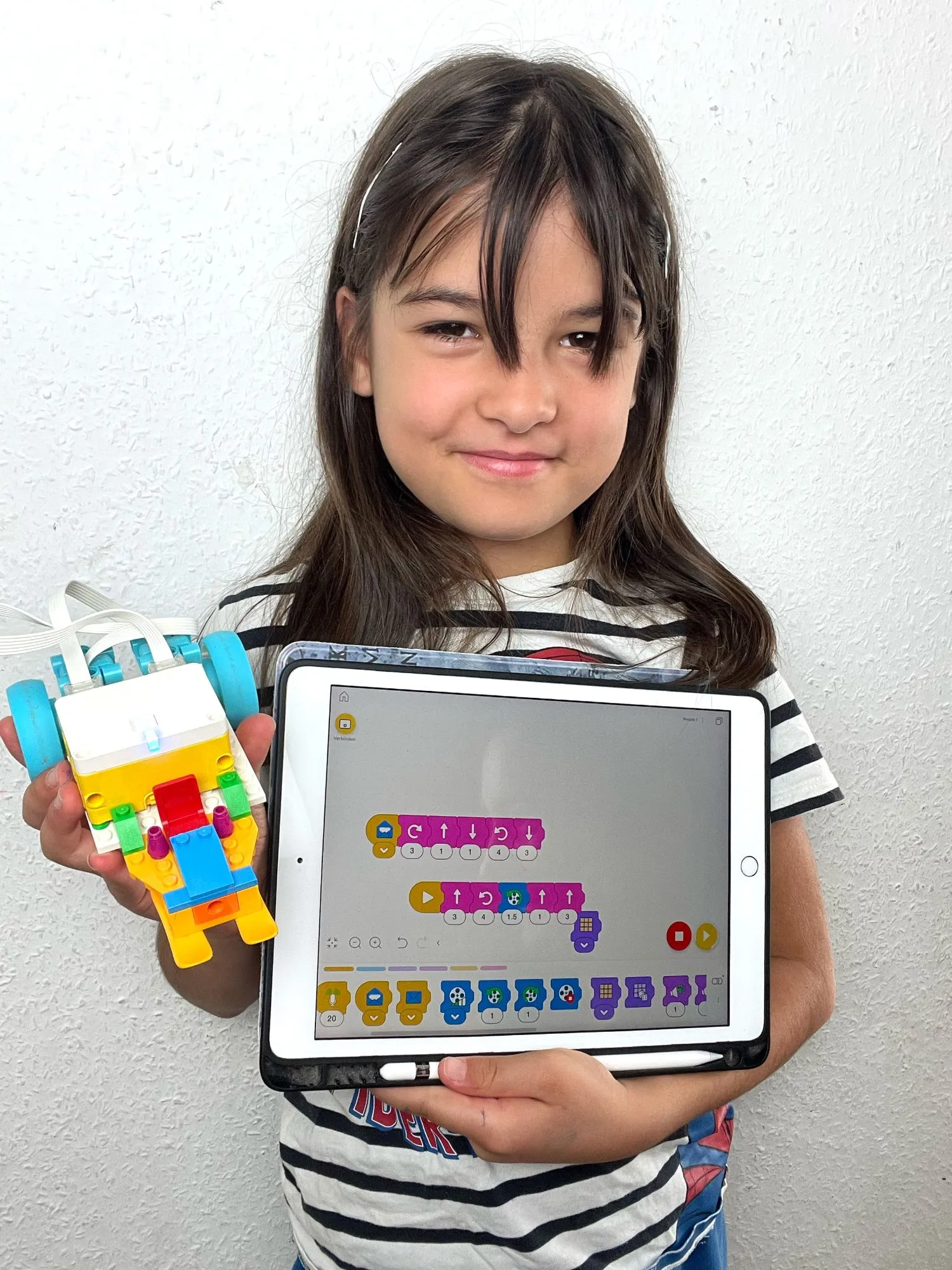 Mädchen zeigt ihren LEGO® Education SPIKE Roboter und das Programm auf dem Tablet